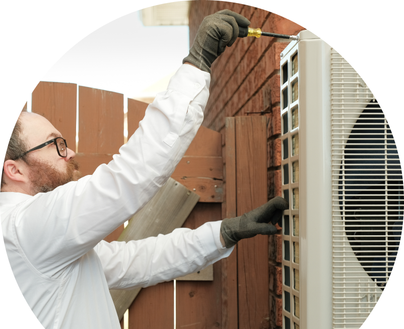 Oosterveld service personnel working on an AC condenser, using a screwdriver to secure the unit’s panel outdoors beside a wooden fence. Oosterveld service personnel working on an AC condenser, using a screwdriver to secure the unit's panel outdoors beside a wooden fence.