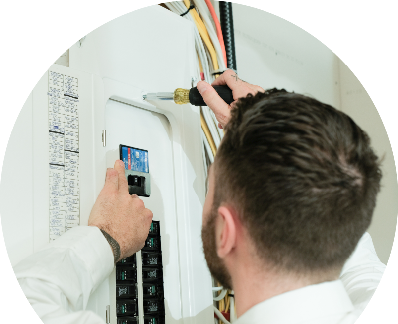 Oosterveld electrician using a screwdriver to perform an electrical panel upgrade, working near organized wiring in a residential wall. Oosterveld electrician using a screwdriver to perform an electrical panel upgrade, working near organized wiring in a residential wall.