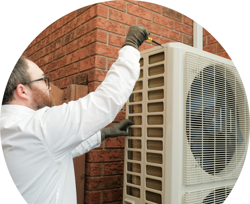 Oosterveld HVAC specialist using a screwdriver to complete a heat pump installation beside a brick wall. Oosterveld HVAC specialist using a screwdriver to complete a heat pump installation beside a brick wall.