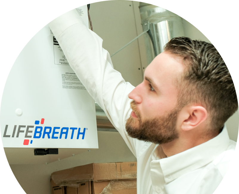 Oosterveld indoor air quality specialist inspects a Lifebreath ventilation unit related to UV air purifiers, with ductwork and boxes in the background. Oosterveld indoor air quality specialist inspects a Lifebreath ventilation unit related to UV air purifiers, with ductwork and boxes in the background.