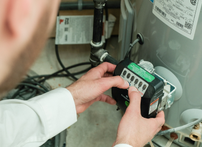 A Oosterveld technician adjusts the control module on a residential water heater, verifying proper operating settings. A Oosterveld technician adjusts the control module on a residential water heater, verifying proper operating settings.